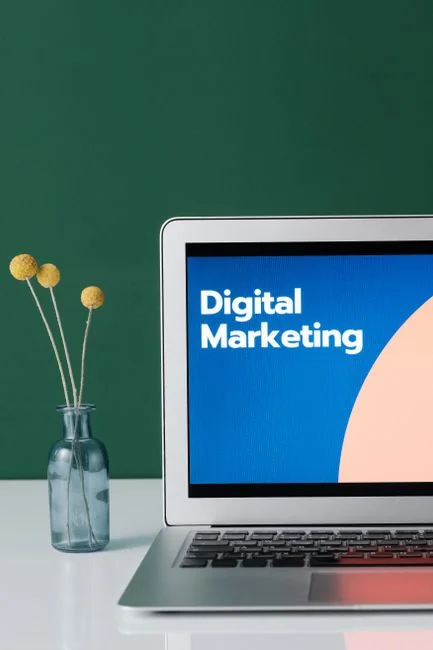 Un espace de travail moderne où des mains examinent des données marketing sur un ordinateur portable et des documents papier.
